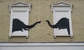 Black spraypainted elephant heads face each other from two white-painted blocked-out windows, with their trunks reaching out towards each other