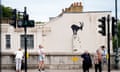People stand in front of the wall painted with Banksy's mountain goat artwork