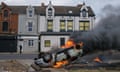 An upturned car burns after it was set on fire in front of houses in Middlesbrough