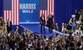 a woman and man on blue stage as a crowd cheers