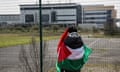 A person wrapped in a Palestinian flag stands outside the Instro Precision arms factory in Sandwich, Kent