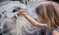A girl using ice-cream in a cone to paint a mess on a window