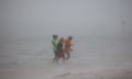 Three people wading in the sea in stormy conditions.