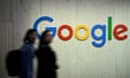 Two people walk next to a Google sign
