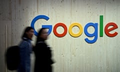 Two people walk next to a Google sign