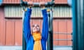 Woman hanging from bar in exercise park.