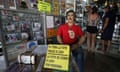 A statue of a man wearing a red shirt sits inside a souvenir shop, with magnets and other memorabilia hanging up.
