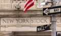 An outside view of the New York Stock Exchange building, a beige building with an American flag hanging outside