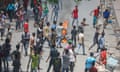 Dozens of young men carrying sticks walk past a burning motorcycle in the middle of a road