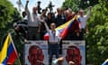 A woman waves and holds the Venezuelan flag from the center of a truck filled with people and decorated with political posters